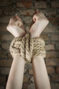 Hands tied with rope using special bondage knots.